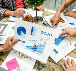 Table covered with financial charts and documents.