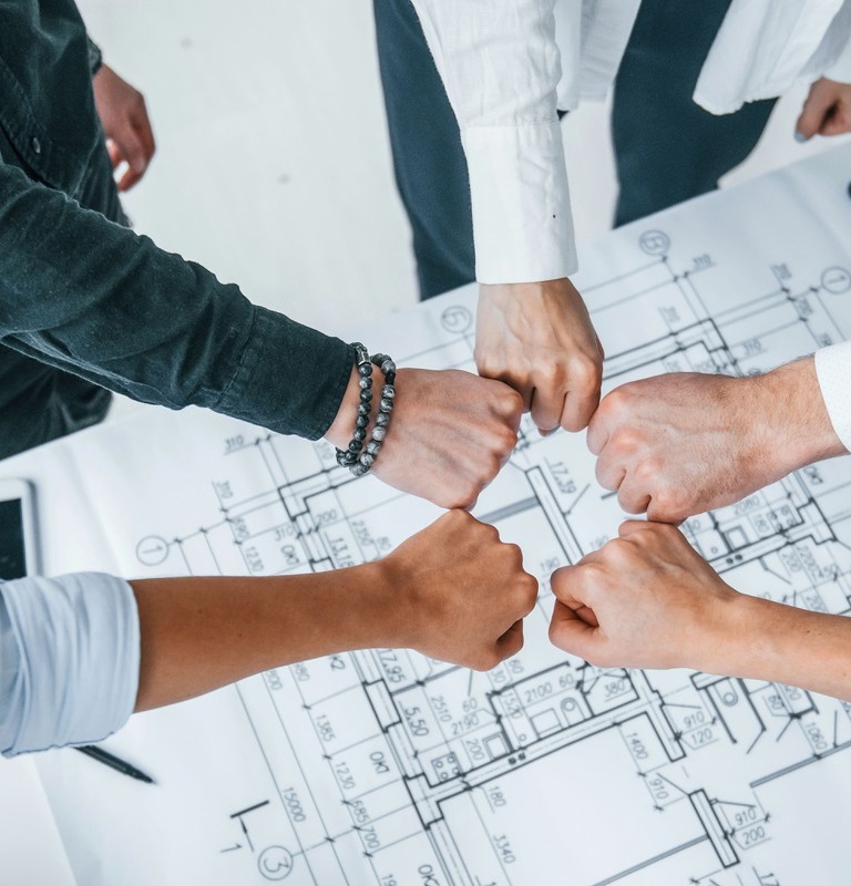 Hands of business people celebrating successful company merger in office over plans lying on table.