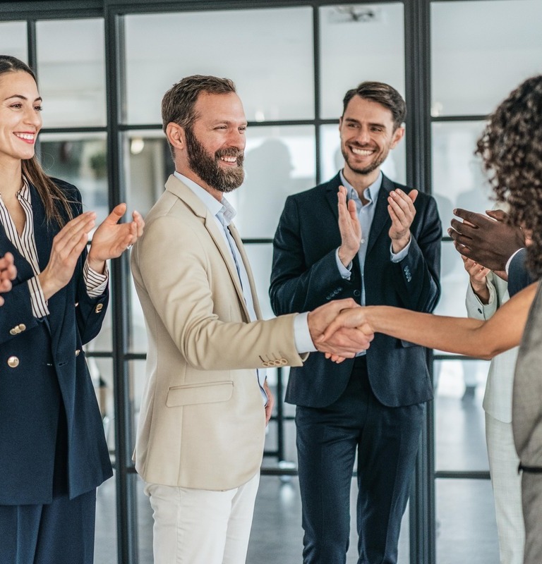 Group of businessmen in the office, two of them shake hands for successful business, colleagues applaud.