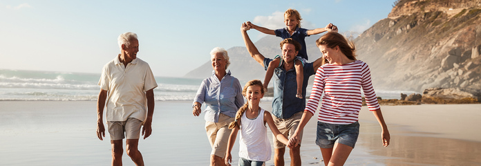 A joyful family spanning three generations enjoys a hike along the beach.