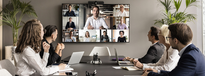 A group gathered around a table for a video conference meeting.