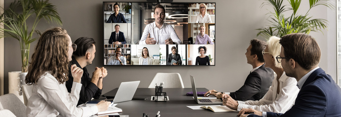 A group gathered around a table for a video conference meeting.